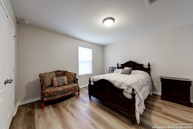 bedroom with light wood-type flooring and a textured ceiling