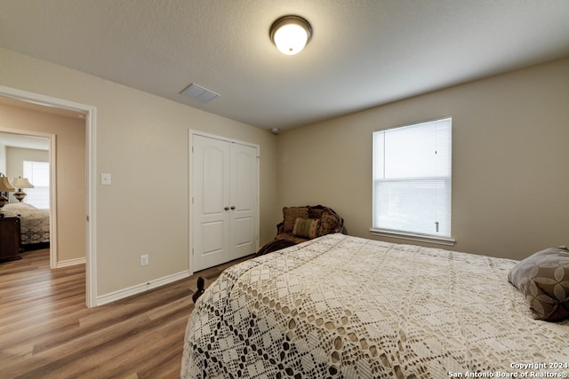 bedroom with wood-type flooring, a textured ceiling, and a closet