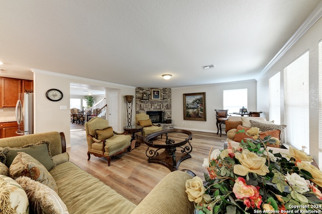 living room with light wood-type flooring, a fireplace, and crown molding