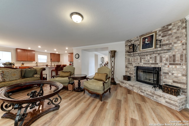 living room with a brick fireplace, light wood-type flooring, and crown molding