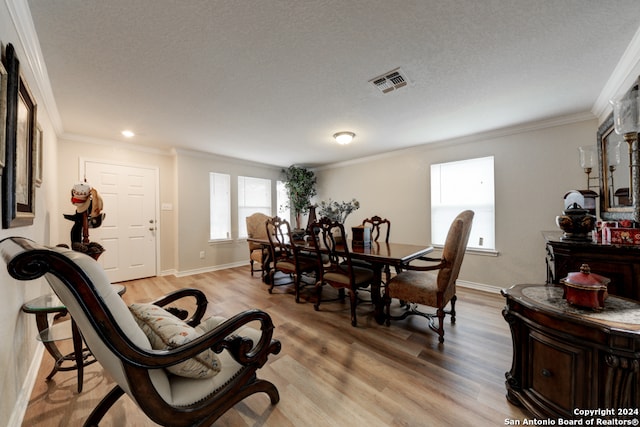 dining space with a textured ceiling, light hardwood / wood-style flooring, and crown molding