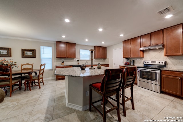 kitchen with stainless steel electric range, light stone counters, crown molding, a kitchen breakfast bar, and a center island