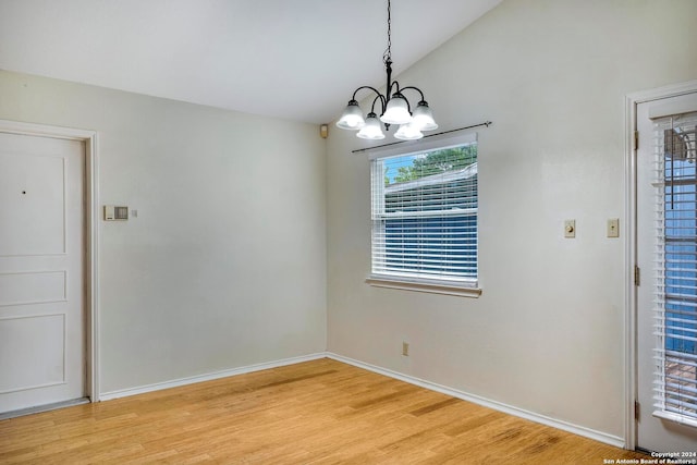 unfurnished dining area with a chandelier, vaulted ceiling, and light hardwood / wood-style floors