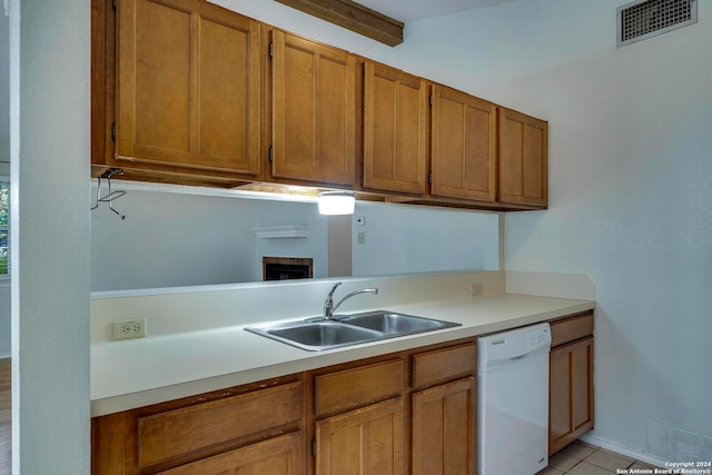 kitchen featuring dishwasher, a brick fireplace, sink, and light tile patterned floors