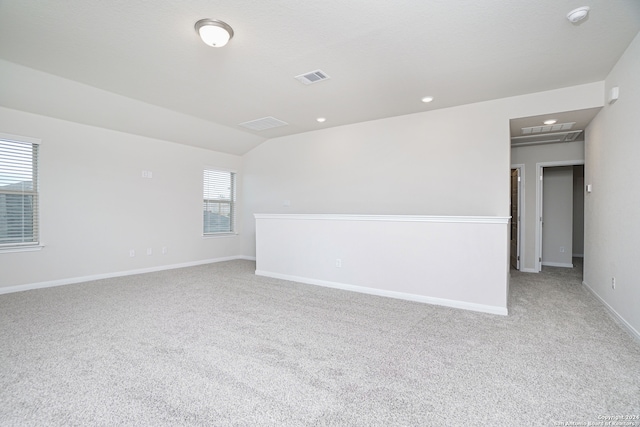 spare room featuring light colored carpet, plenty of natural light, and vaulted ceiling