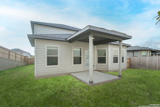 back of house featuring a lawn and a patio area