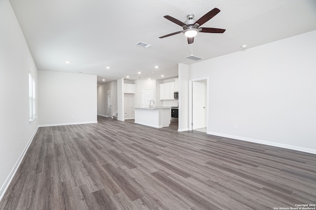 unfurnished living room with dark hardwood / wood-style flooring, sink, and ceiling fan