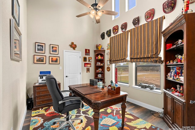 office area featuring dark hardwood / wood-style flooring, ceiling fan, and a high ceiling