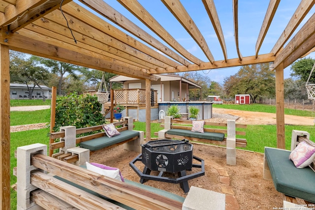 view of patio / terrace with a wooden deck, a storage shed, a fire pit, and a pergola