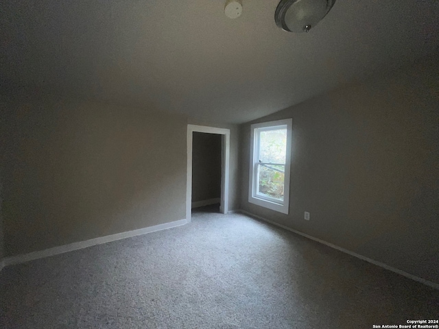 carpeted empty room featuring lofted ceiling