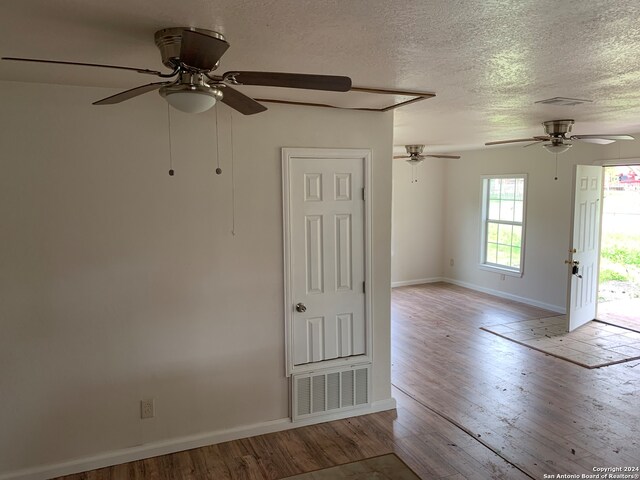 spare room featuring ceiling fan, light hardwood / wood-style flooring, and a textured ceiling