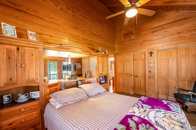 bedroom featuring multiple closets, wood walls, ceiling fan, and lofted ceiling with beams