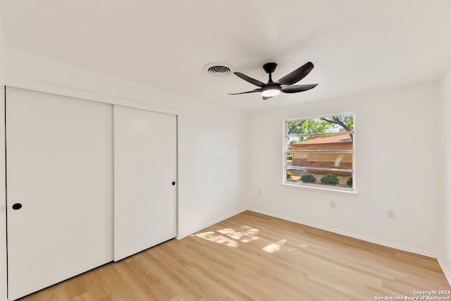 unfurnished bedroom featuring a closet, light wood-type flooring, and ceiling fan