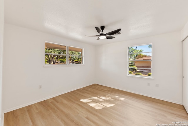 unfurnished room featuring ceiling fan, a textured ceiling, a healthy amount of sunlight, and light hardwood / wood-style flooring