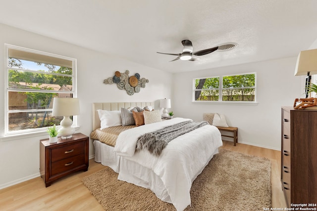 bedroom with light hardwood / wood-style floors, ceiling fan, and multiple windows