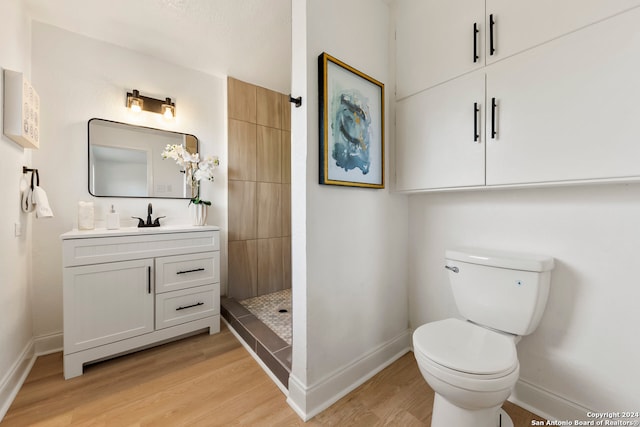 bathroom with hardwood / wood-style floors, walk in shower, vanity, and toilet