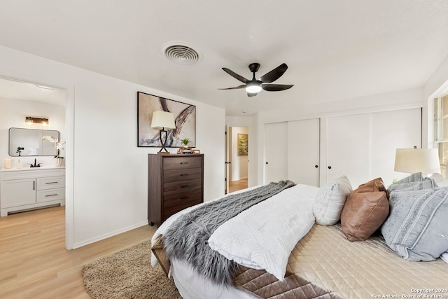 bedroom featuring light hardwood / wood-style floors, ceiling fan, ensuite bath, and sink