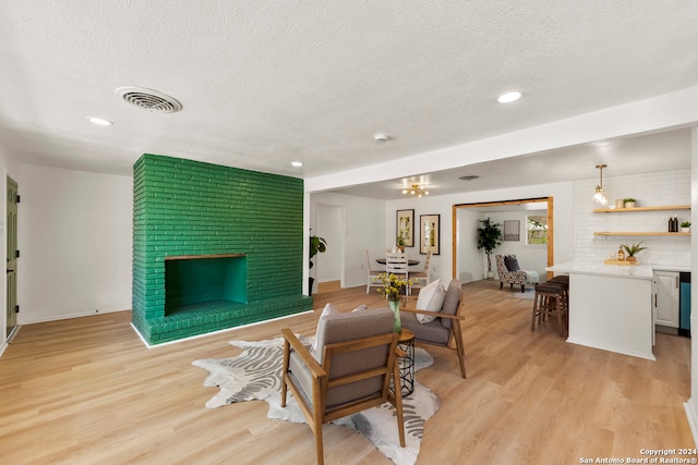 living room featuring a fireplace, a textured ceiling, and light wood-type flooring