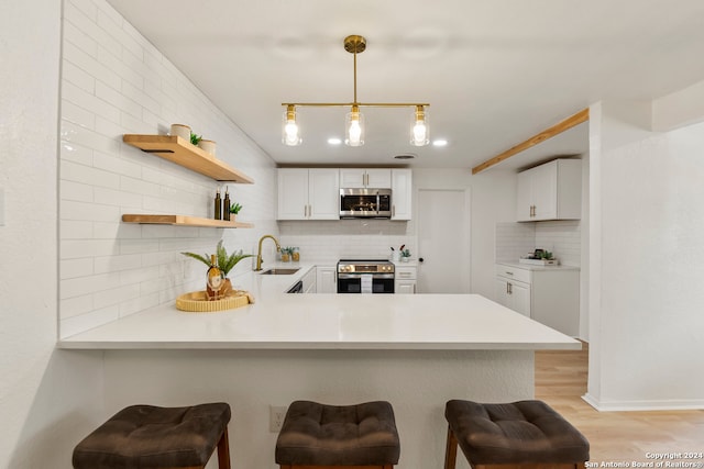 kitchen featuring white cabinetry, kitchen peninsula, and stainless steel appliances