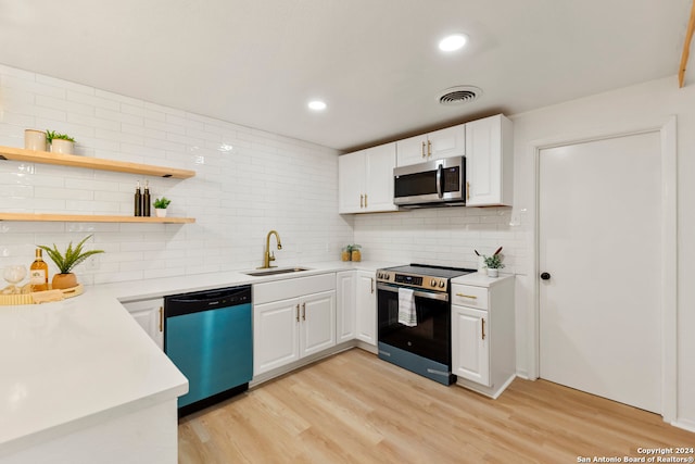 kitchen with stainless steel appliances, white cabinets, sink, and light wood-type flooring