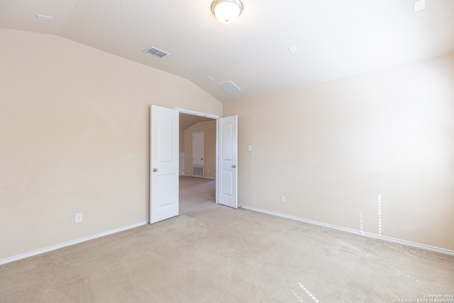 empty room with vaulted ceiling and light carpet