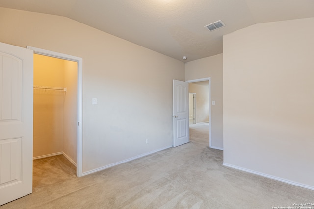 unfurnished room featuring lofted ceiling and light carpet