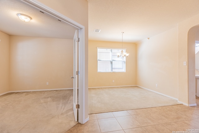 unfurnished room with light colored carpet and a chandelier