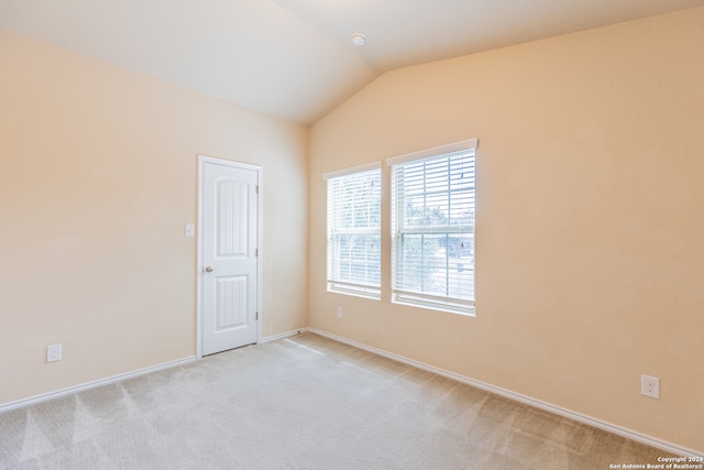 carpeted empty room with lofted ceiling