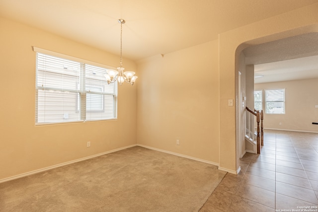 carpeted spare room with a notable chandelier