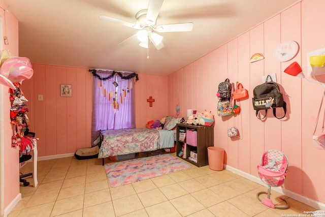 bedroom featuring wood walls, ceiling fan, and light tile patterned floors