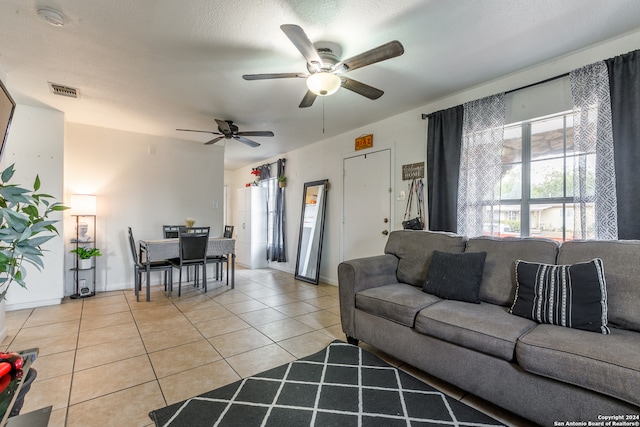 living room featuring a textured ceiling, light tile patterned floors, and ceiling fan