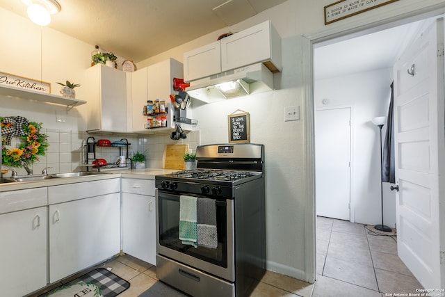 kitchen with stainless steel range with gas cooktop, sink, tasteful backsplash, light tile patterned floors, and white cabinets