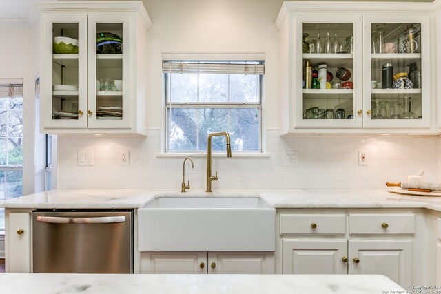 kitchen with stainless steel dishwasher, white cabinets, sink, and tasteful backsplash