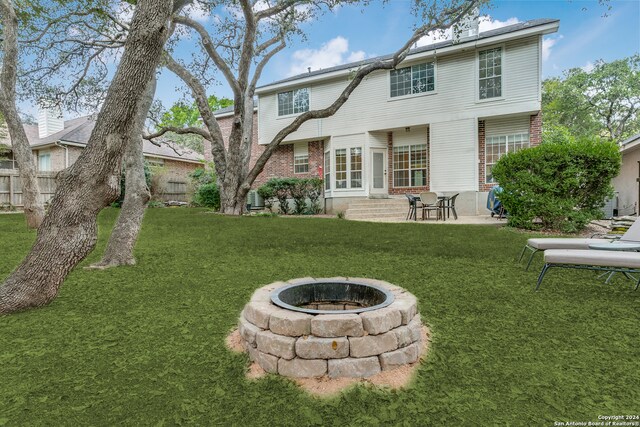 rear view of property featuring a fire pit, a patio, and a yard