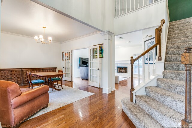 foyer with dark hardwood / wood-style flooring, decorative columns, a notable chandelier, and ornamental molding