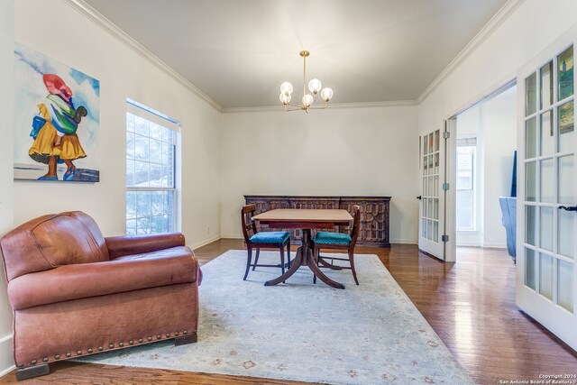 dining space featuring dark wood-type flooring, ornamental molding, french doors, and a notable chandelier