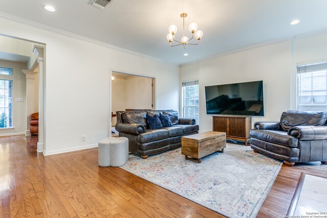 living room with light wood-type flooring, a wealth of natural light, and crown molding