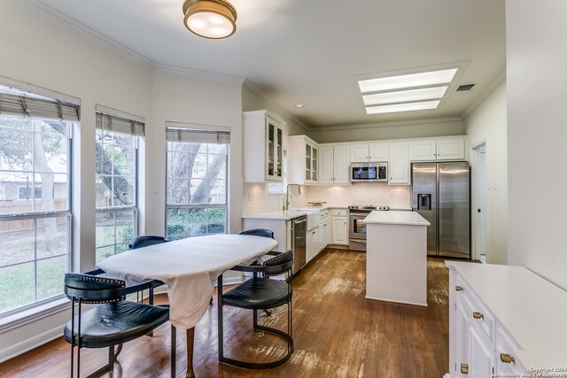 kitchen featuring white cabinets, appliances with stainless steel finishes, a center island, and dark hardwood / wood-style flooring