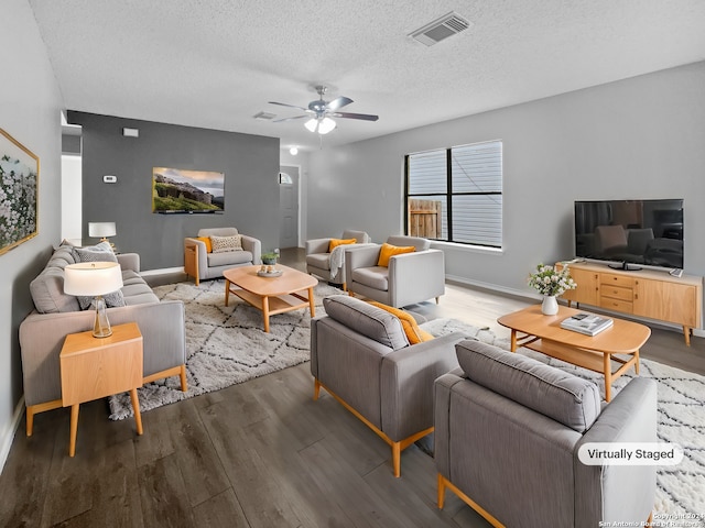 living room with ceiling fan, wood-type flooring, and a textured ceiling