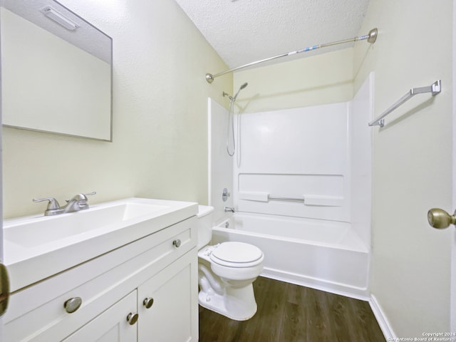 full bathroom featuring a textured ceiling, hardwood / wood-style floors, vanity, shower / bath combination, and toilet