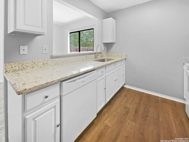 kitchen with wood-type flooring, light stone counters, sink, white cabinets, and dishwasher