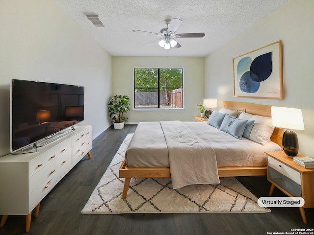 bedroom featuring dark hardwood / wood-style flooring, a textured ceiling, and ceiling fan