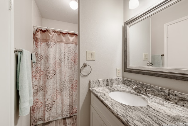 bathroom with vanity, hardwood / wood-style floors, a shower with shower curtain, and a textured ceiling