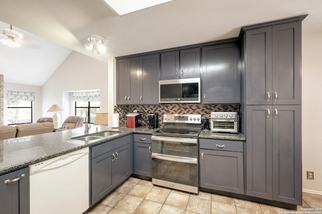 kitchen with stainless steel appliances, light tile patterned floors, backsplash, lofted ceiling, and gray cabinets