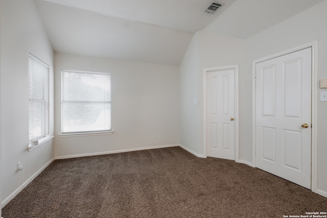 unfurnished bedroom with dark colored carpet and lofted ceiling