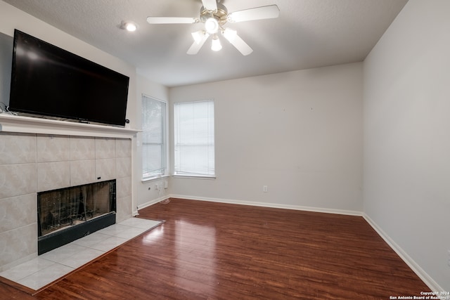 unfurnished living room featuring a textured ceiling, light wood-type flooring, a fireplace, and ceiling fan