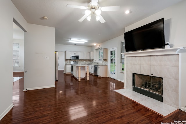 living room with a tiled fireplace, light hardwood / wood-style floors, and ceiling fan