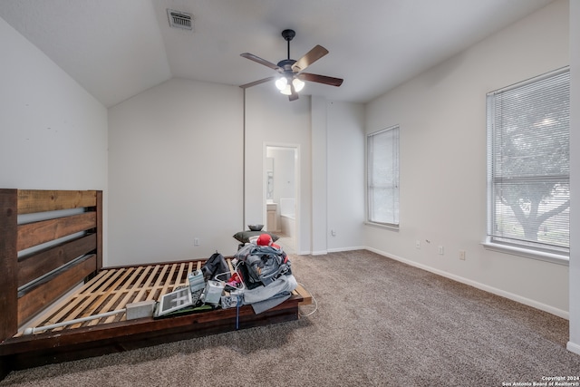 carpeted bedroom with connected bathroom, multiple windows, lofted ceiling, and ceiling fan