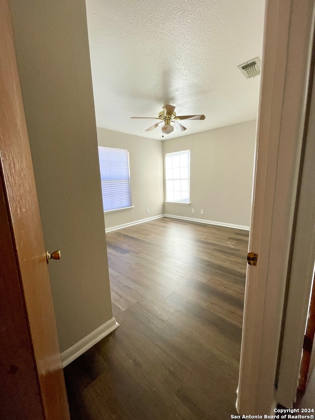 unfurnished room featuring ceiling fan, dark hardwood / wood-style flooring, and a textured ceiling