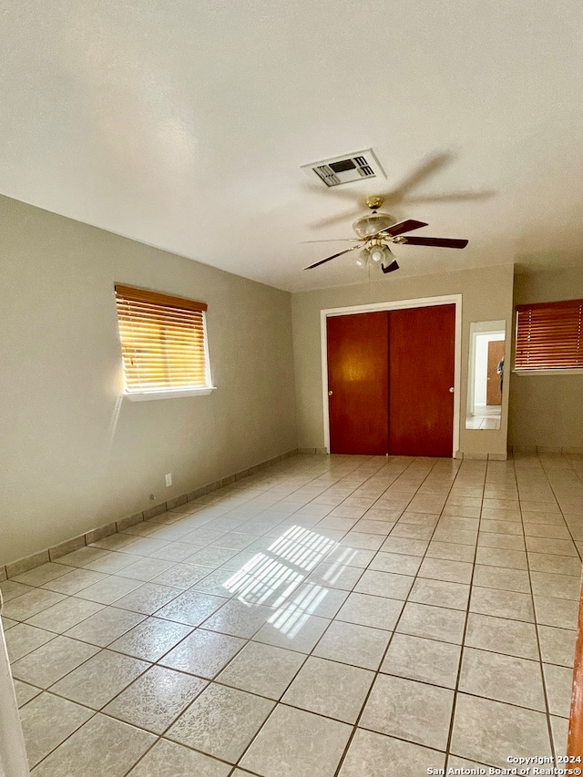 unfurnished bedroom featuring ceiling fan, light tile patterned floors, and a closet